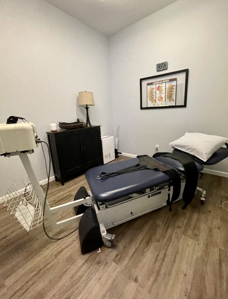 room with chiropractic decompression table with lumbar spine photo on wall in Steadfast Spine and Sport in Warrenton MO